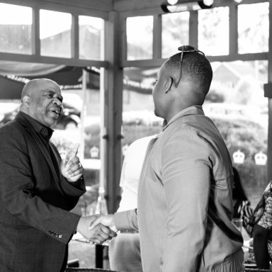 Two men shaking hands in a welcoming indoor setting.
