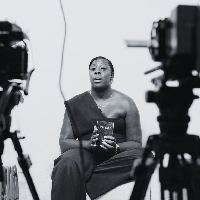 A person sitting and holding a book, framed by two cameras.