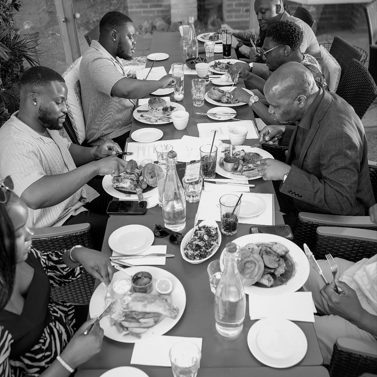 A group of people dining together at a table with various dishes and drinks.